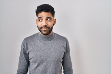 Fototapeta premium Hispanic man with beard standing over white background smiling looking to the side and staring away thinking.