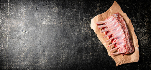 Rack of raw lamb on paper on the table. © Artem Shadrin