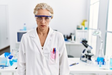 Middle age blonde woman working at scientist laboratory skeptic and nervous, frowning upset because of problem. negative person.