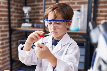 Adorable hispanic boy student looking molecules at laboratory classroom