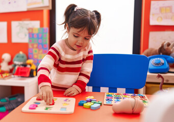Fototapeta premium Adorable hispanic girl playing with maths puzzle game standing at kindergarten