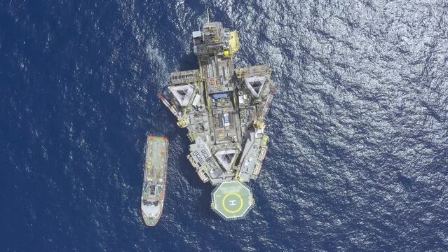 Aerial view from a drone of an offshore jack up rig, oil platform and offshore supply vessels at the offshore location during day time
