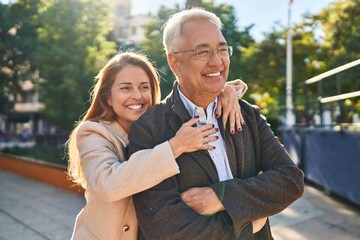 Middle age man and woman couple hugging each other standing at park