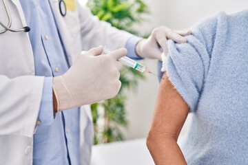 Middle age man and woman doctor vaccinating patient at clinic
