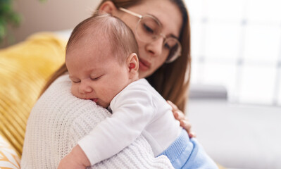 Mother and son hugging each other sitting on sofa at home
