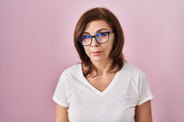 Middle age hispanic woman standing over pink background depressed and worry for distress, crying angry and afraid. sad expression.