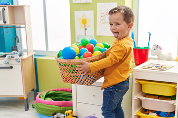 Adorable caucasian boy smiling confident playing with balls at kindergarten