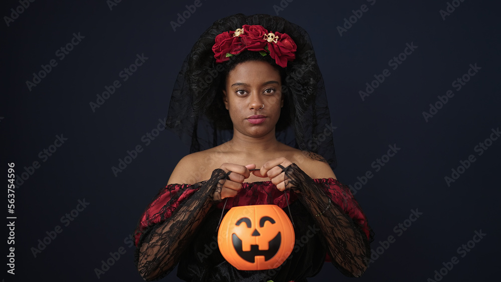 Sticker African american woman wearing katrina costume holding halloween pumpkin basket over isolated black background