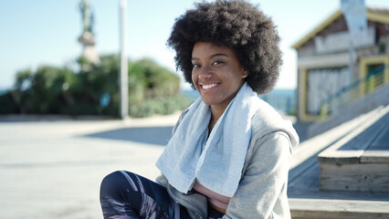 Fototapeta na wymiar African american woman wearing sportswear sitting on bench at street