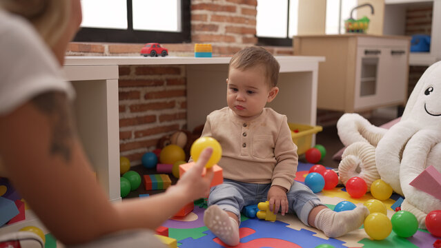 Adorable toddler playing with plastic construction blocks looking ball at kindergarten