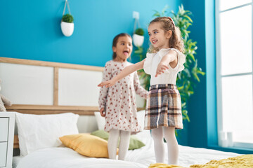 Fototapeta na wymiar Two kids smiling confident dancing on bed at bedroom