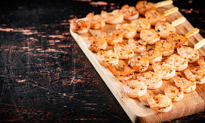 Grilled shrimp on skewers on a cutting board. 