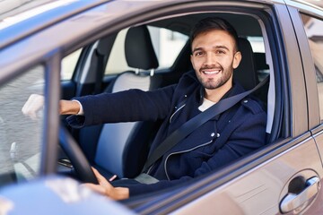 Young hispanic man smiling confident driving car at street