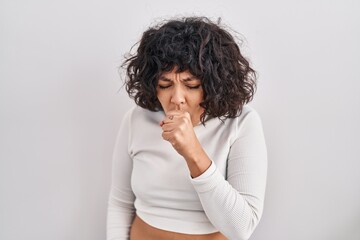 Hispanic woman with curly hair standing over isolated background feeling unwell and coughing as symptom for cold or bronchitis. health care concept.