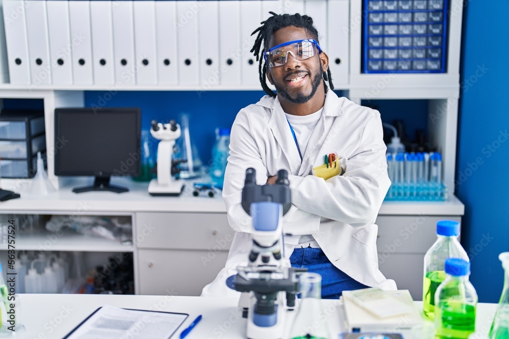 Wall mural African man with dreadlocks working at scientist laboratory happy face smiling with crossed arms looking at the camera. positive person.