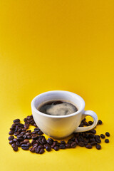  One cup of espresso and coffee beans over yellow background