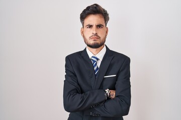 Young hispanic man with tattoos wearing business suit and tie skeptic and nervous, disapproving expression on face with crossed arms. negative person.