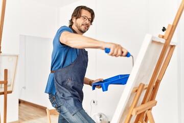 Middle age caucasian man smiling confident drawing using paint roller at art studio