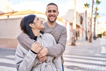 Man and woman couple smiling confident hugging each other standing at street