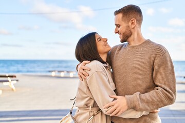Man and woman couple smiling confident hugging each other standing at seaside