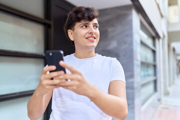Non binary man smiling confident using smartphone at street