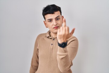 Non binary person standing over isolated background showing middle finger, impolite and rude fuck...