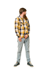 Naklejka premium Young adult redhead man with a long beard standing full body isolated looks aside smiling, cheerful and pleasant.