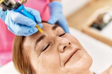 Middle age caucasian woman having anti-aging face treatment at beauty center