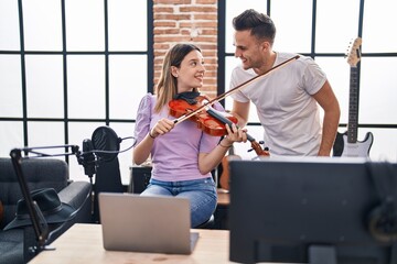 Man and woman musicians having online violin lesson at music studio