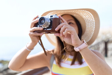 Young asian woman tourist using vintage camera at seaside