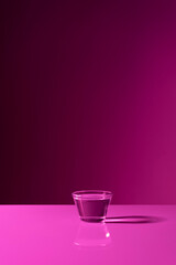 Glass with water on purple background