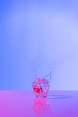 Strawberry drink explosion with purple and lilac lights in studio