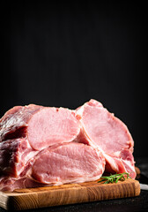 Large chunks of raw pork on a wooden cutting board. 