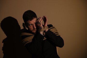 Scared man tied up and taken hostage on dark background. Space for text