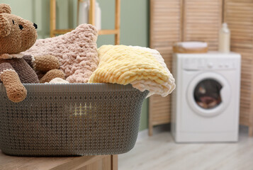 Laundry basket with soft blankets and toy in bathroom, closeup. Space for text