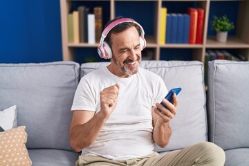 Middle age man listening to music sitting on sofa at home