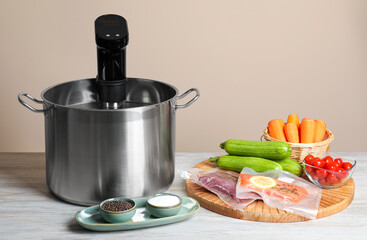 Thermal immersion circulator in pot and ingredients on white wooden table. Vacuum packing for sous...