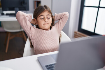 Fototapeta premium Adorable hispanic girl student using laptop relaxed with hands on head at classroom