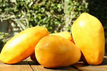 Fresh ripe papaya fruits on wooden table outdoors