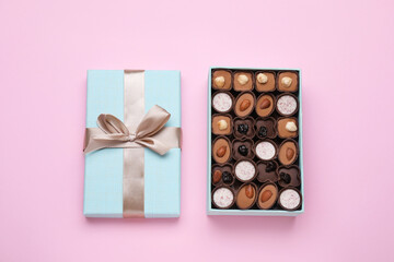 Open box of delicious chocolate candies on pink background, flat lay