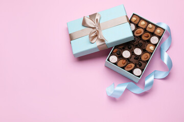 Open box of delicious chocolate candies on pink background, flat lay. Space for text