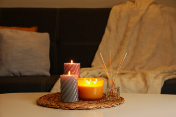 Beautiful candles and reed air freshener on white table indoors. Cosy atmosphere