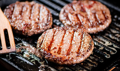 Cooking a delicious grilled burger on a pan with oil bubbles.