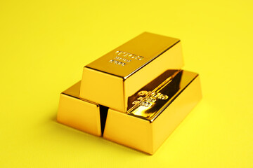 Stack of shiny gold bars on yellow background