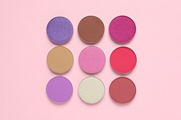 Different beautiful eye shadows on pink background, flat lay