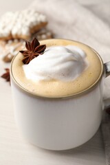 Cup of delicious eggnog with anise star on wooden table, closeup
