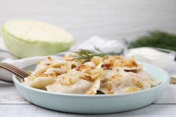 Cooked dumplings (varenyky) with tasty filling, fried onions and dill on wooden table, closeup