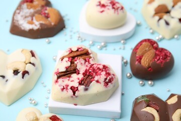 Tasty chocolate heart shaped candies with nuts on light blue background