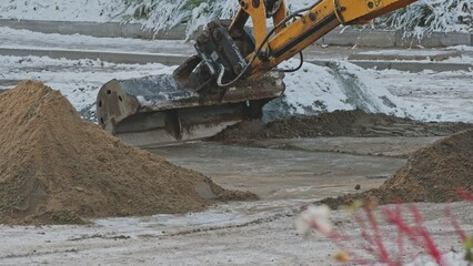 Fototapeta premium Industrial Excavator Scoop Distributing Sand on Street Surface During Winter Maintenance Roadworks