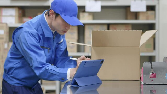 荷物を検品してタブレットPCでチェックする男性